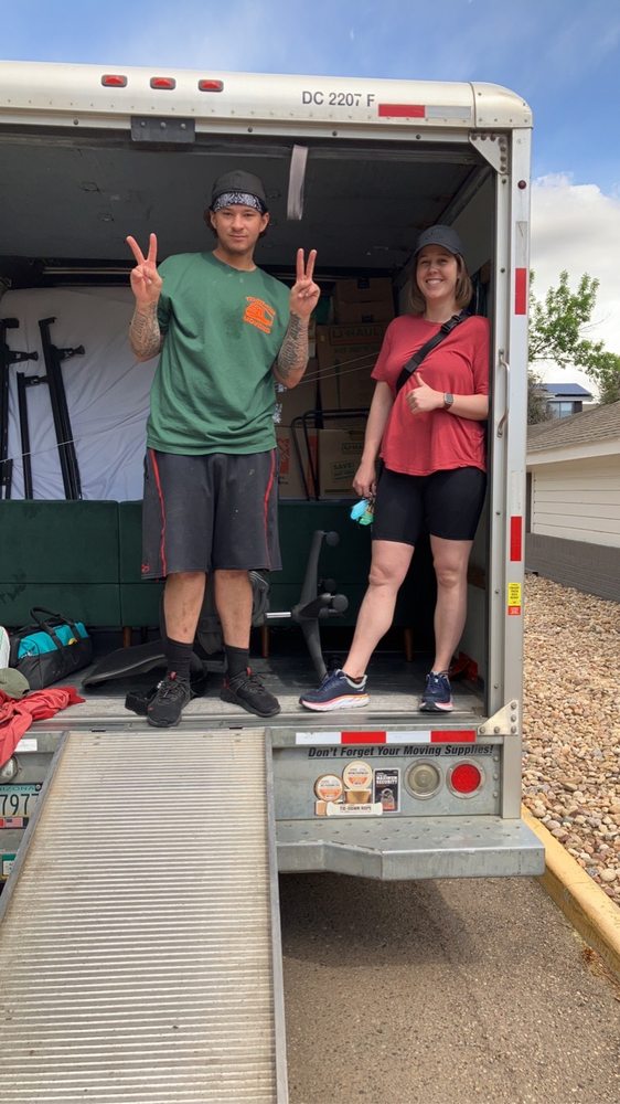A mover and a smiling customer giving peace signs on a truck ramp
