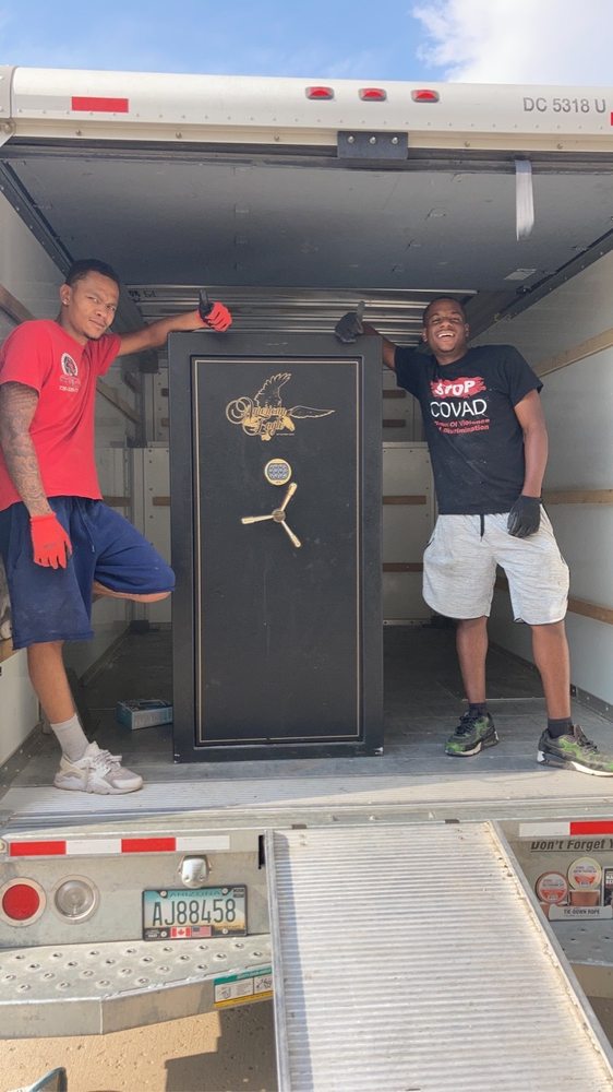 Movers loading a heavy safe into a truck
