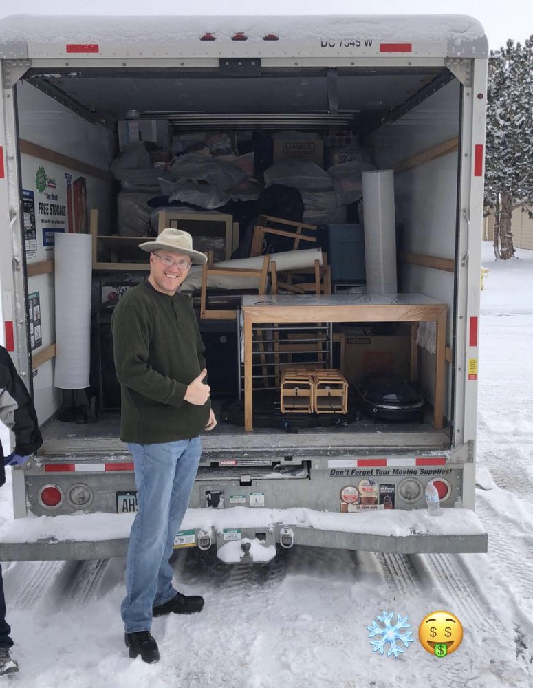 A smiling customer giving a thumbs up during a snowy winter move